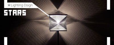 The image showcases a modern table lamp with a geometric mesh shade, projecting intricate patterns o