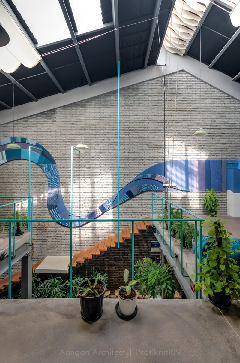 Atrium view showing the blue metal slide wrapping around brick walls and steel columns with daylight above