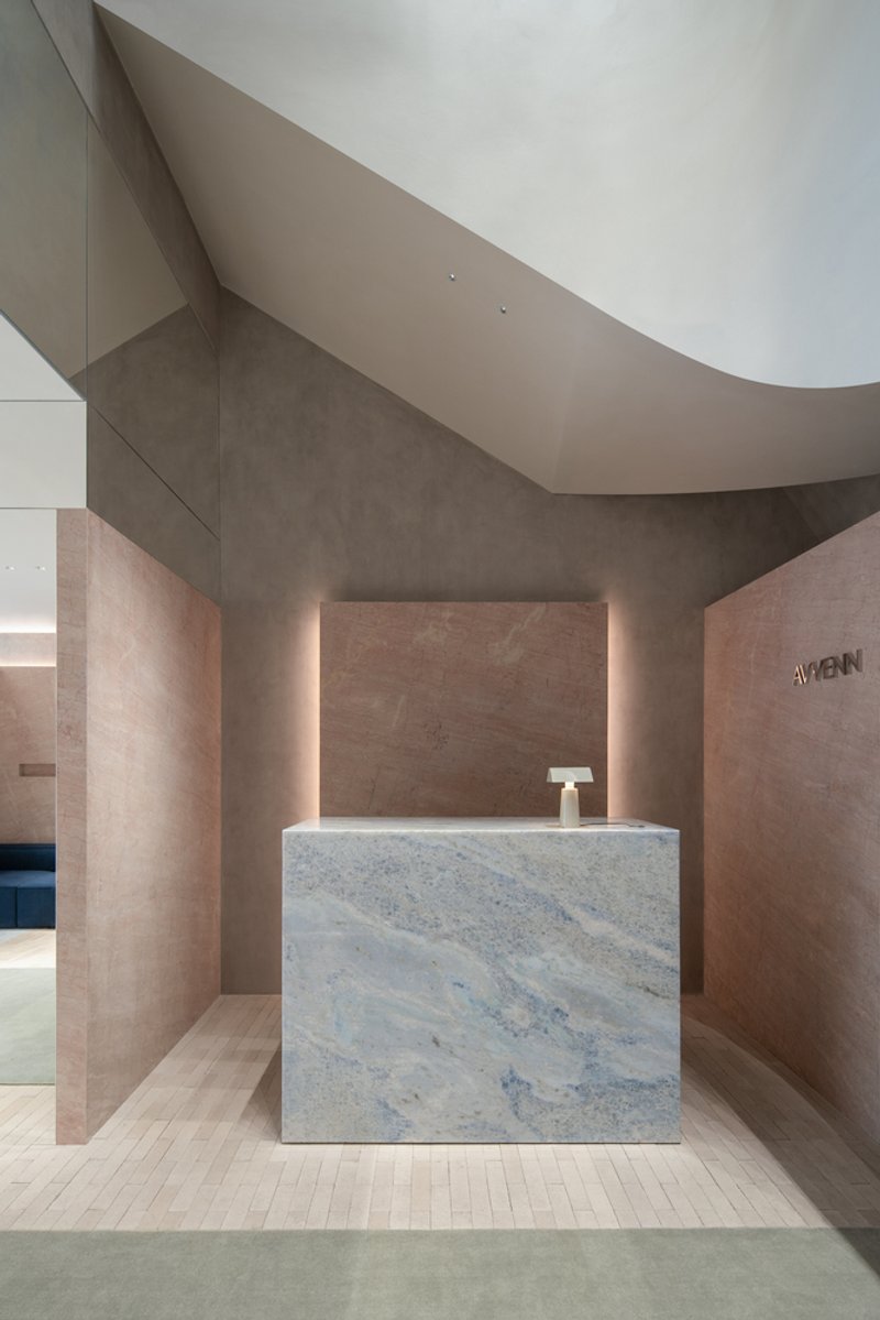 Veined marble reception counter beneath curved ceiling with backlit stone wall panels