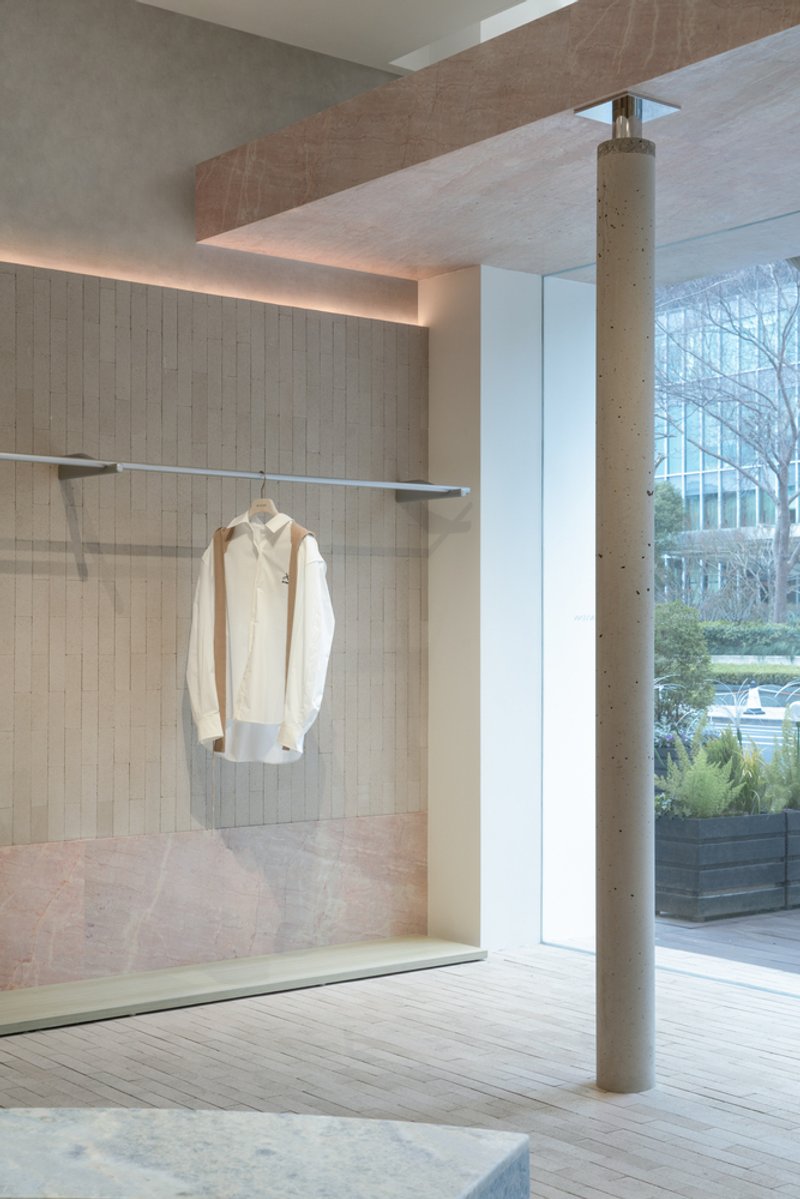 Interior retail space with glass display niche, exposed concrete column and floor-to-ceiling windows overlooking trees