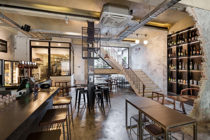 Ground floor evening: full bakery counter with underlit display, shelving, pendant lamps, stair in background