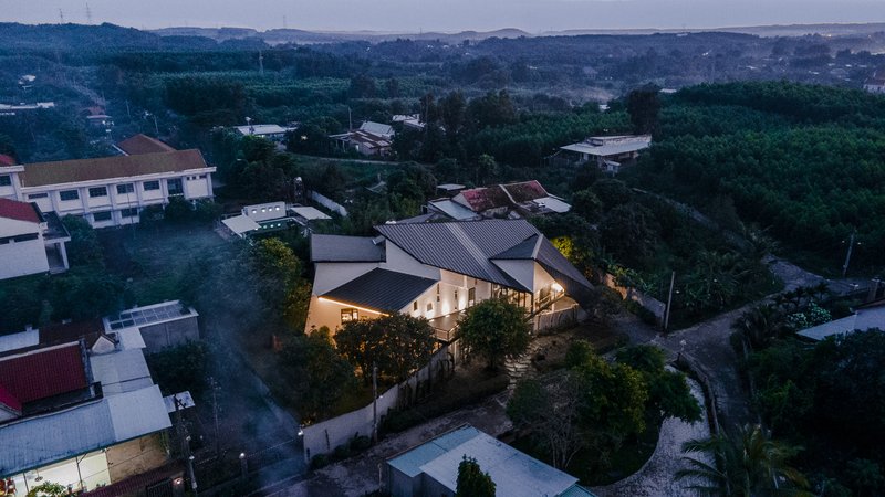 Aerial view of the gabled metal roof structure illuminated at dusk among surrounding residential buildings
