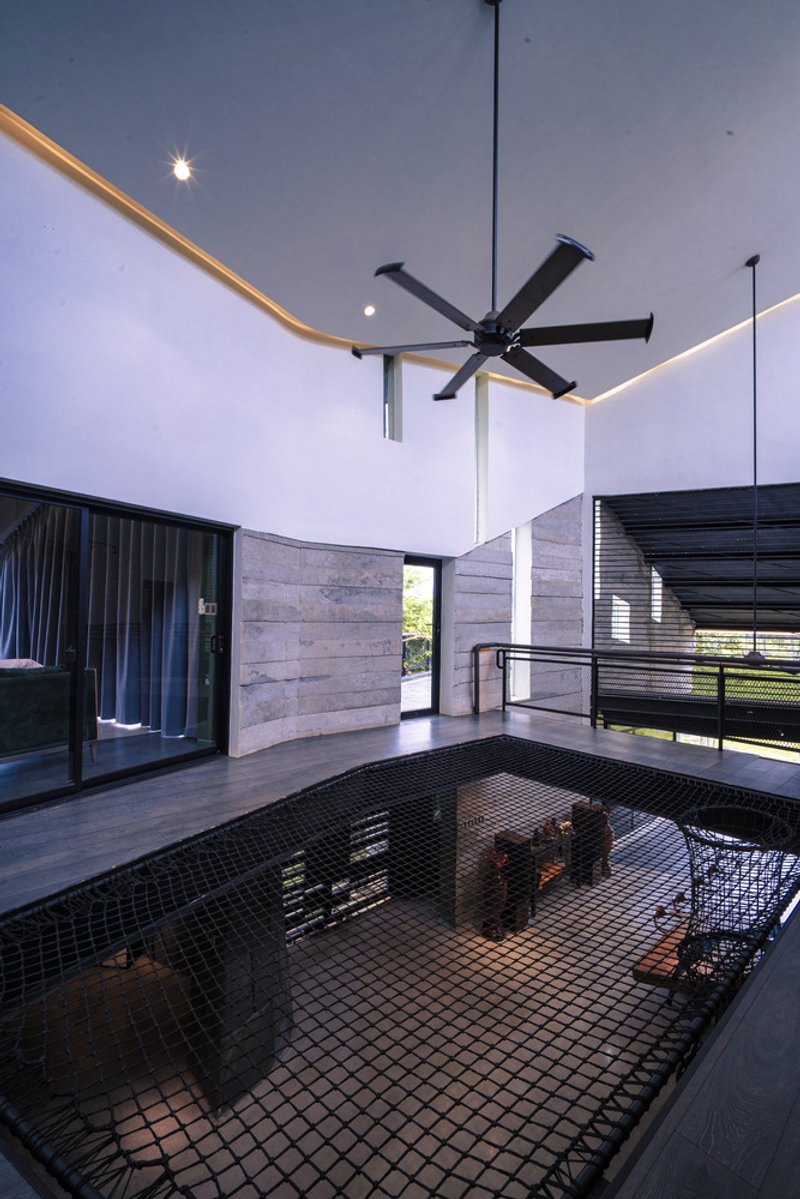Interior courtyard with black mesh floor opening and boardformed concrete walls under an overcast sky