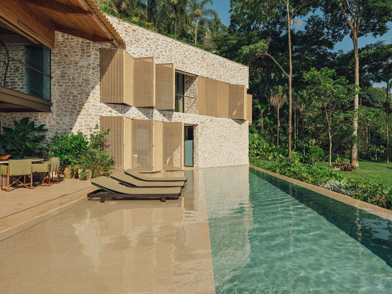 Stone facade with timber shutters and lap pool against dense tropical vegetation