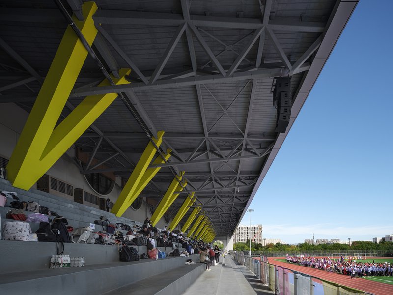Facade detail: concentric circular relief sculpture in concrete panel, large circular window, sports centre beyond