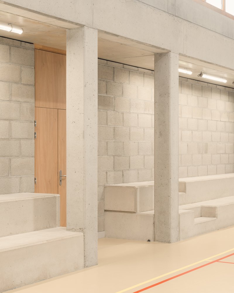 Gymnasium entrance: concrete block walls, concrete columns, timber door, built-in bench