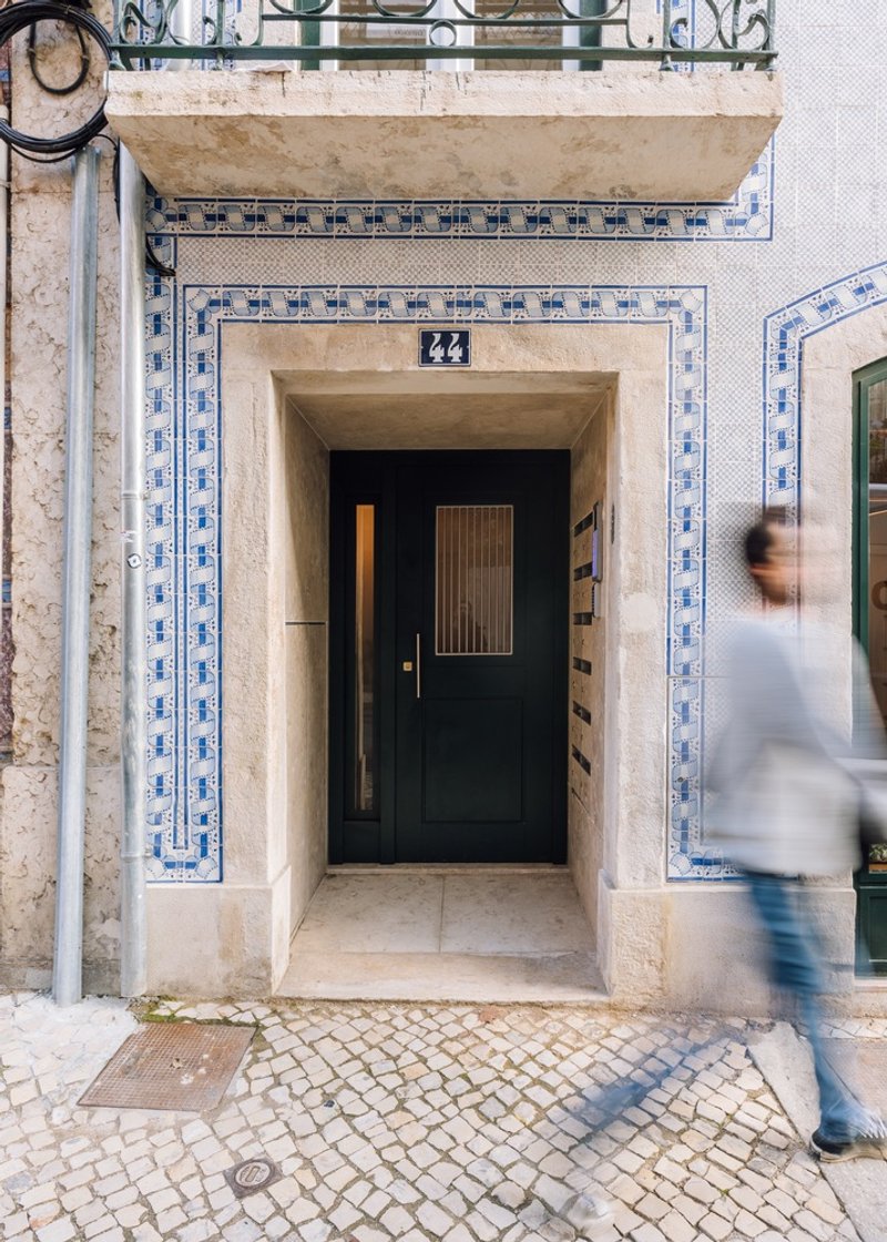 Street entry with limestone surround and blue azulejo tile border as a pedestrian passes by