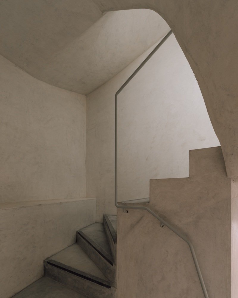 Concrete stairwell with chamfered corners and vaulted ceiling in soft natural light