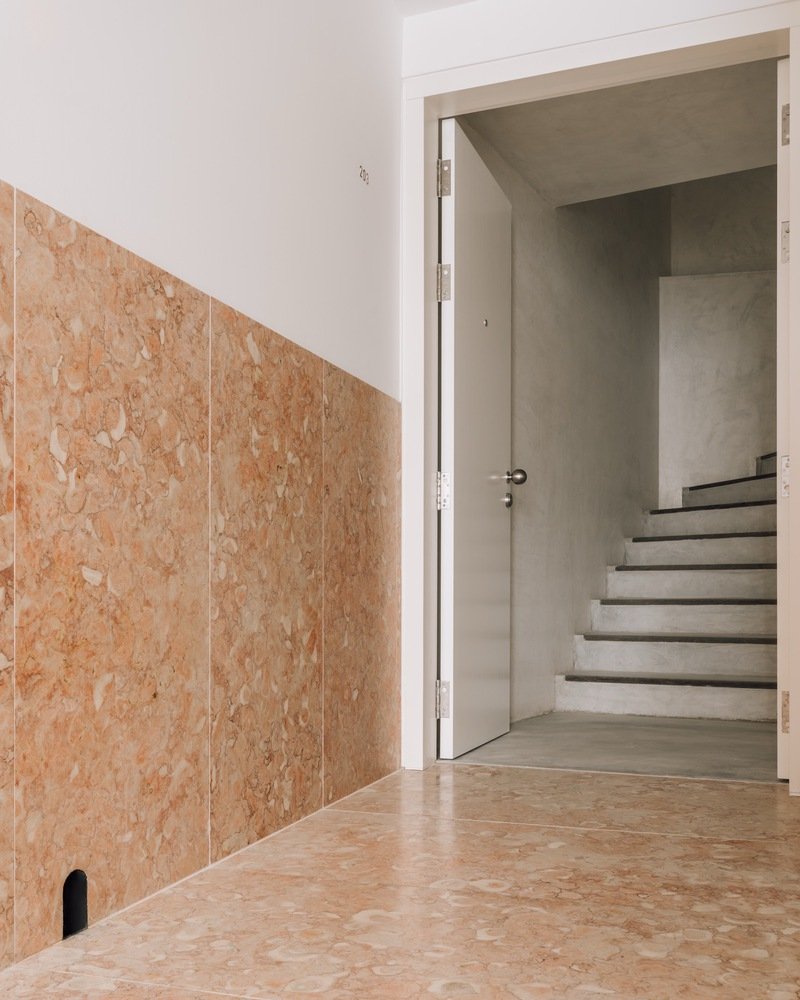 Cork panel wall alongside an open doorway revealing concrete stairs in natural light
