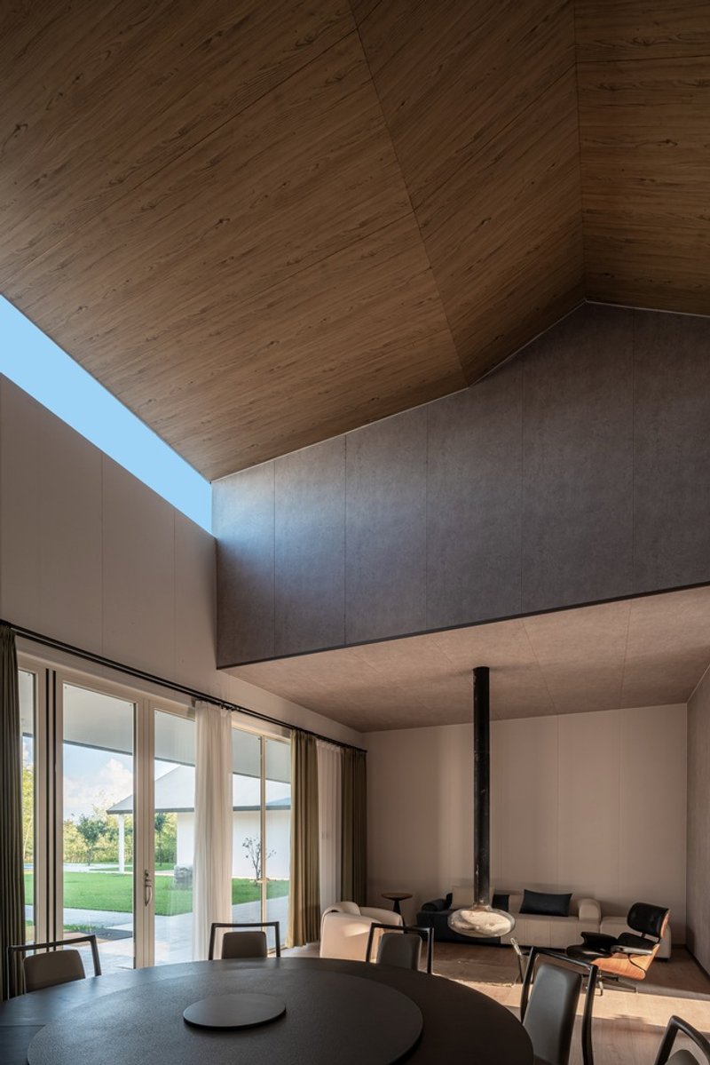 Interior dining space with timber-clad vaulted ceiling and clerestory skylight above painted walls