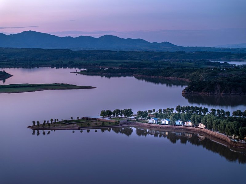 Aerial view of the island compound on a lake at dusk with distant mountains