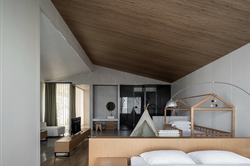Bedroom interior with sloped timber ceiling and white paneled walls framing multiple sleeping zones