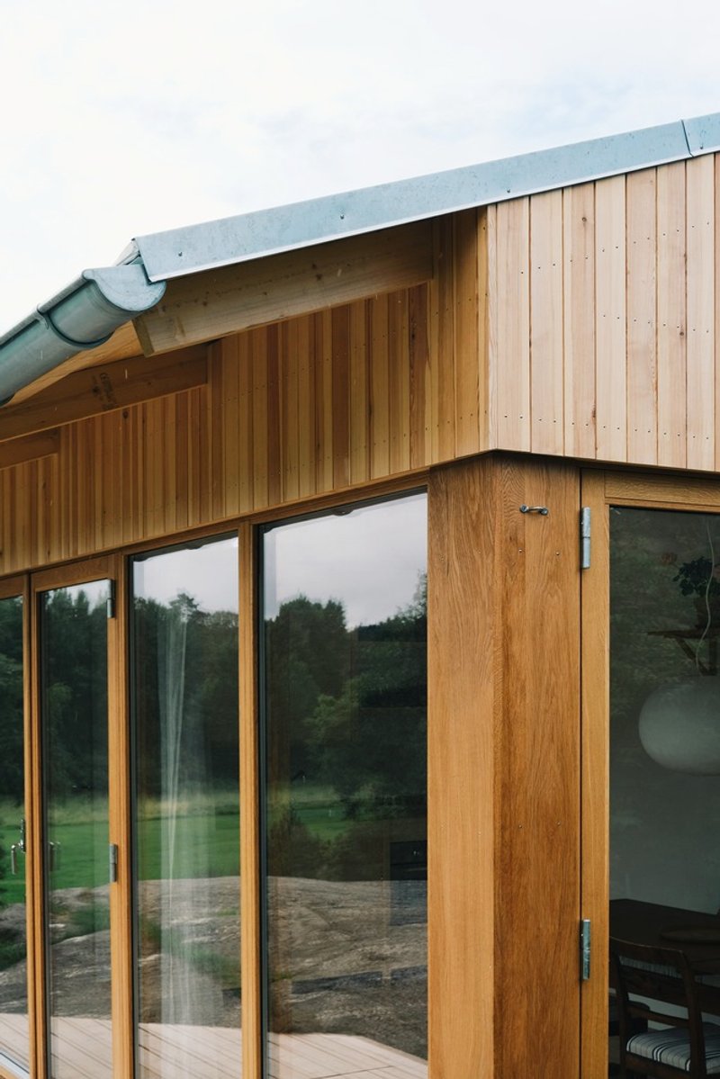 Close-up of the zinc-clad eave edge meeting vertical timber cladding and a glass corner