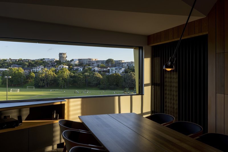 Dining area with horizontal window framing distant parkland views in late afternoon sunlight
