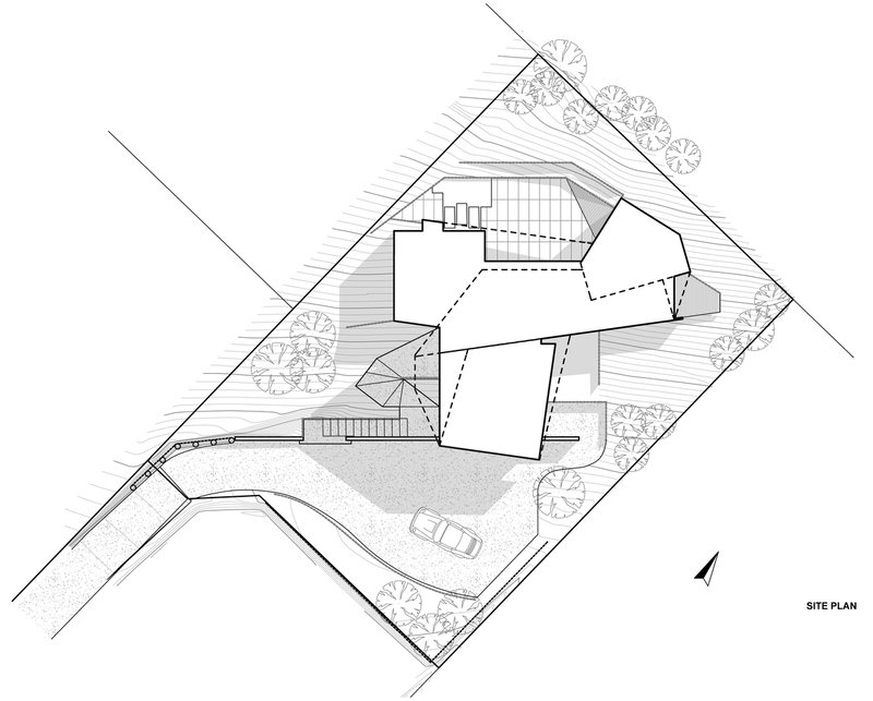 Site plan drawing showing an angular building footprint with outdoor spaces and a curved driveway