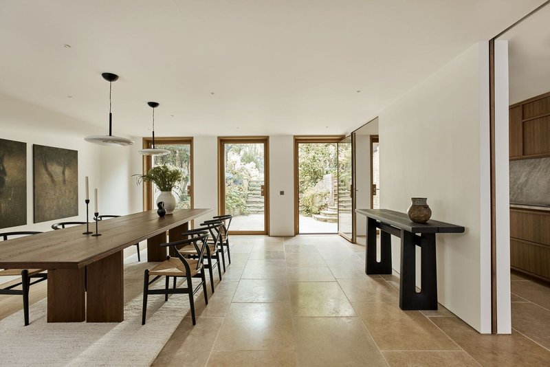 Open plan dining area with timber table and glazed doors framing view to garden courtyard beyond
