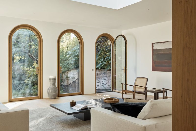 Living room with three arched timber-framed doors opening to a garden courtyard in soft daylight