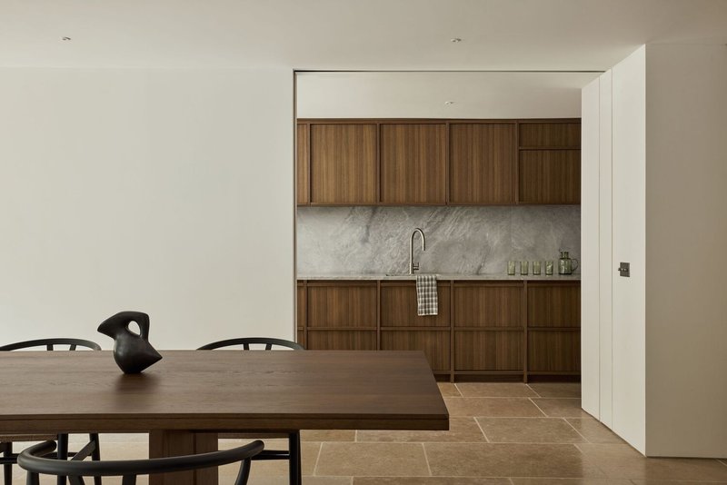 View through doorway to kitchen with walnut veneer cabinetry and white marble backsplash