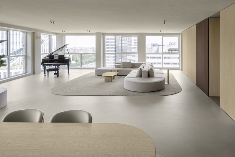 Living room with curved sectional sofa and grand piano positioned near floor-to-ceiling windows