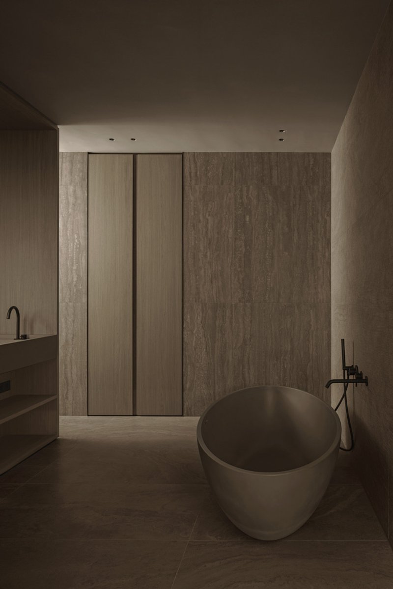 Bathroom with a rounded freestanding tub and floor-to-ceiling timber panels in dim ambient light