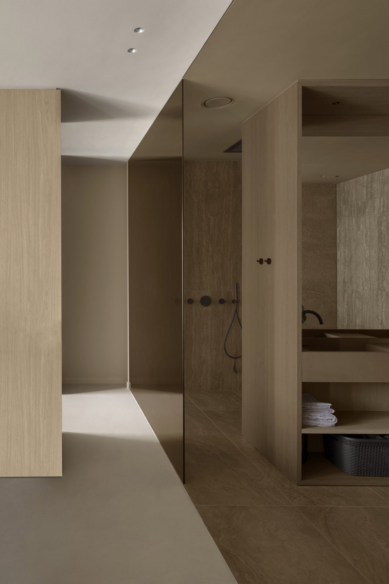 Corridor view into a walk-in shower with timber-paneled walls and open shelving in warm recessed light