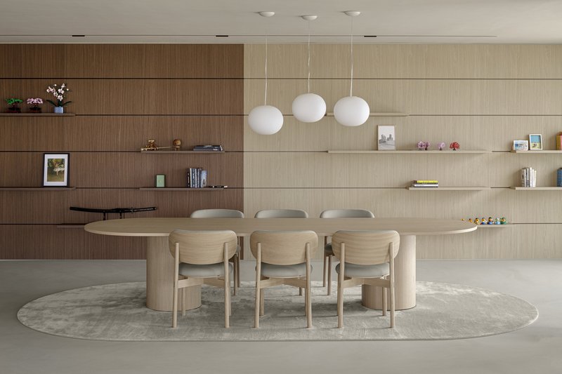 Oval dining table with spherical pendant lights below horizontal wood shelving and display niches