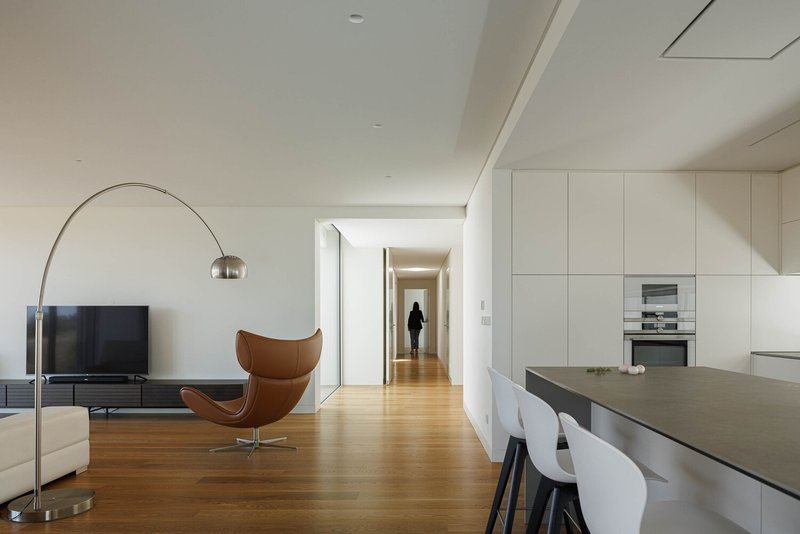 View from kitchen island toward a corridor with a figure walking in soft natural light