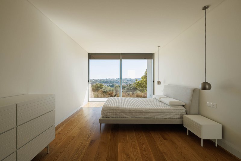 Bedroom with sliding glass door framing views of olive trees and distant hills