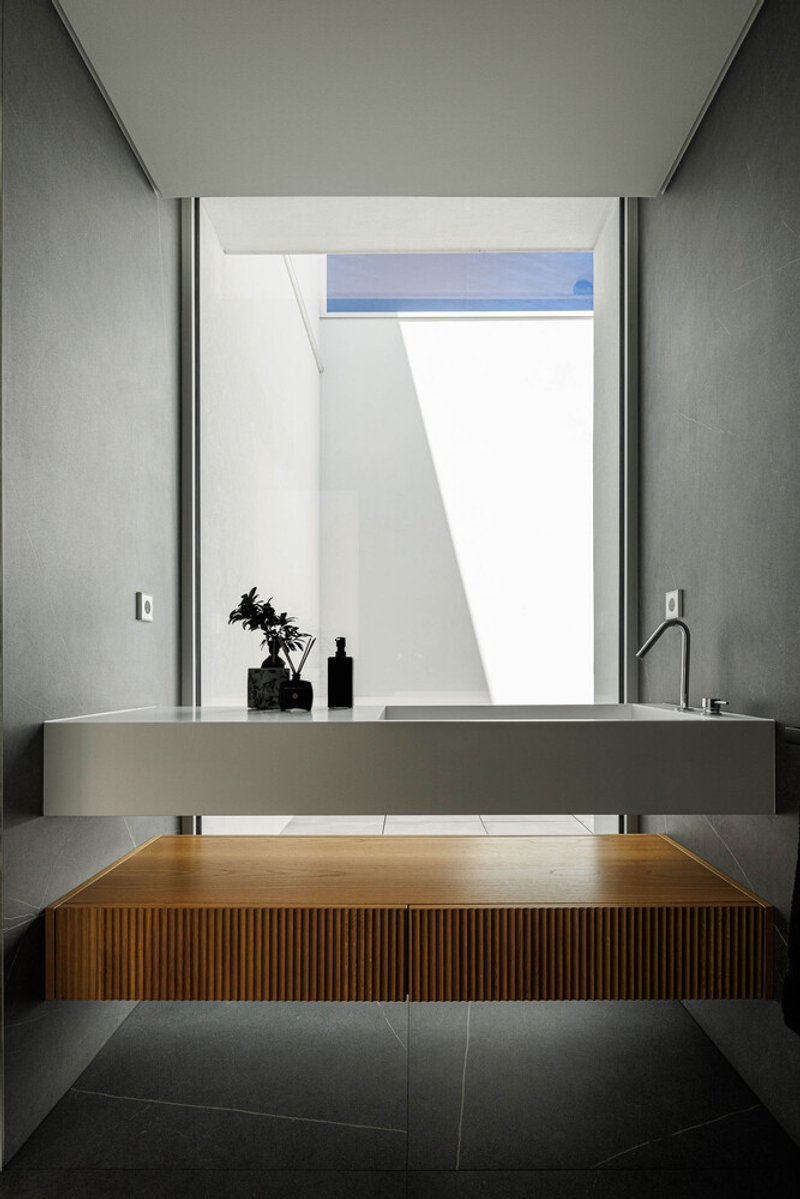 Powder room with floating concrete sink, ribbed timber cabinet below, and skylight framing white walls