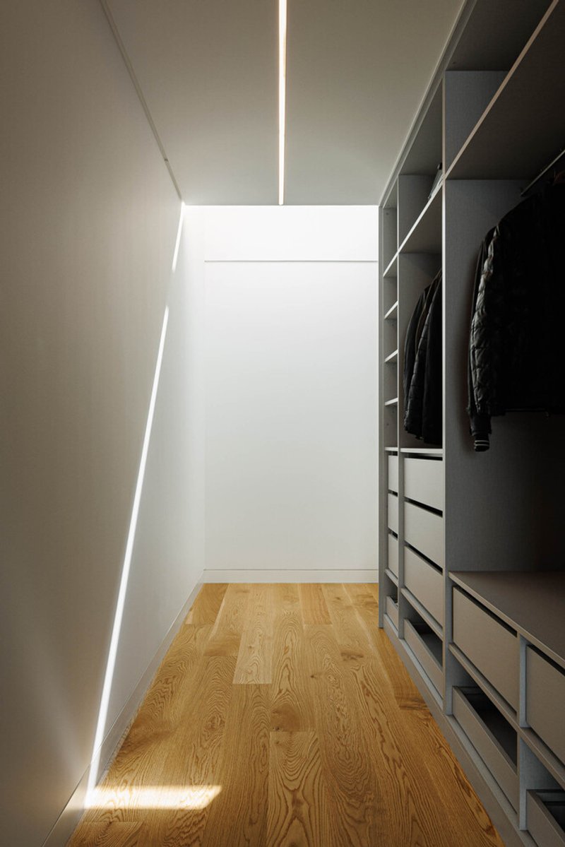 Walk-in closet with continuous LED strip lighting along wall and ceiling joint