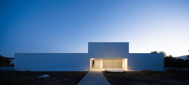 Front elevation at dusk showing illuminated entry and paved walkway under deep blue sky