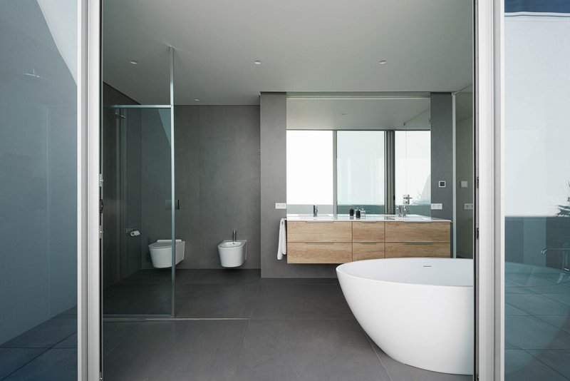 Bathroom interior with freestanding tub, timber vanity, and glass shower enclosure under diffused daylight