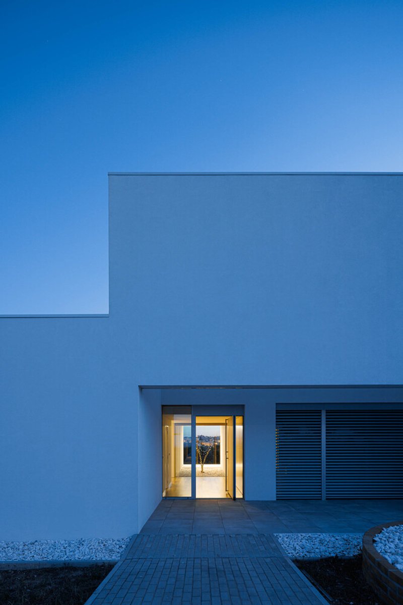 Recessed entry with lit glass door and horizontal louvered panel at twilight
