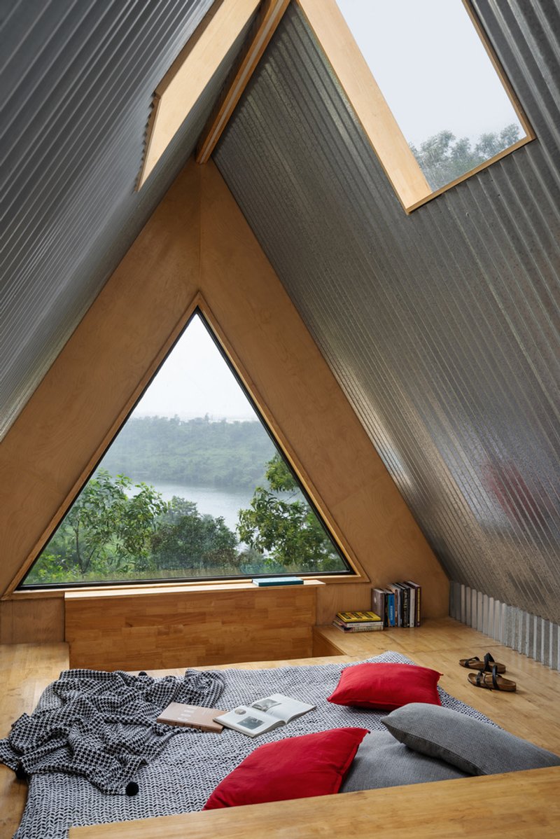 Triangular window framing the view of a lake and hillside under overcast skies