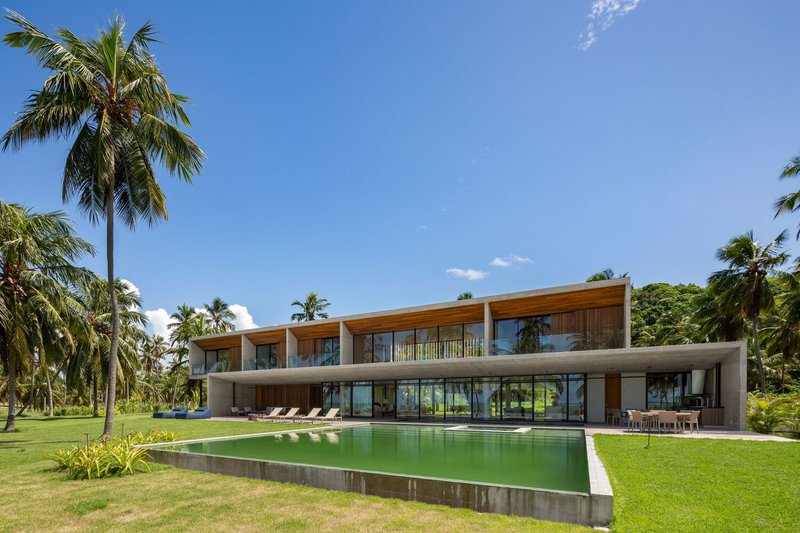 Full garden elevation: two-storey volume with concrete frame, timber upper floor, pool and loungers