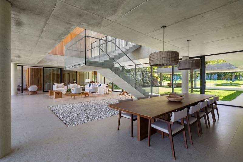 Double-height space: concrete stair with glass balustrade, timber ceiling panel above, pool through window