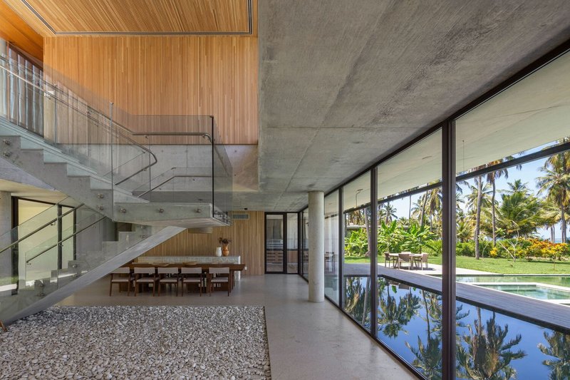 Living and dining from the stair side: concrete column, pebble border, woven pendant lamp, ocean view
