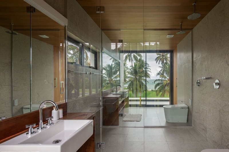 Bathroom: stone walls, timber ceiling, rain shower, window framing palm trees and coastline