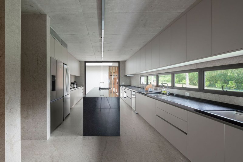 Kitchen: grey stone island, concrete ceiling, strip windows to the garden