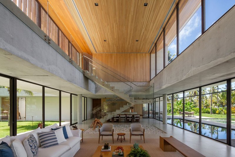 Double-height living room: concrete stair, timber ceiling, full-height glazing on both sides