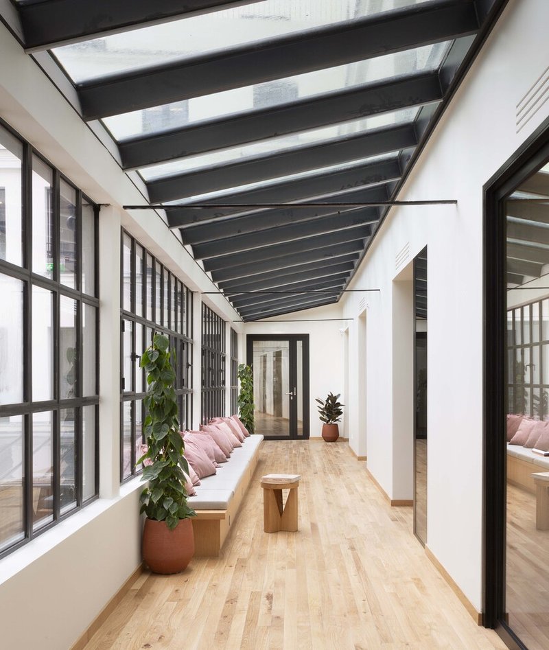 After: glazed gallery corridor, steel-frame roof, oak floor, bench seating, pink cushions, plants