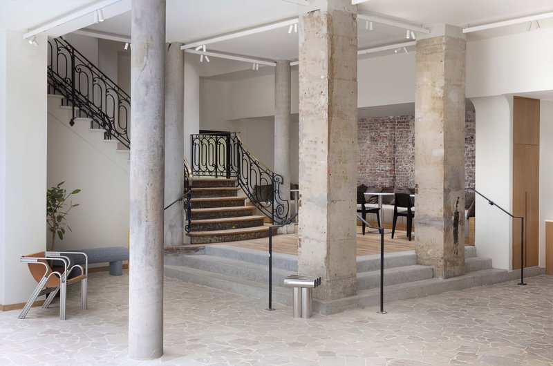 After: grand stone staircase with iron balustrade, exposed columns, stone floor, bench seating, lobby