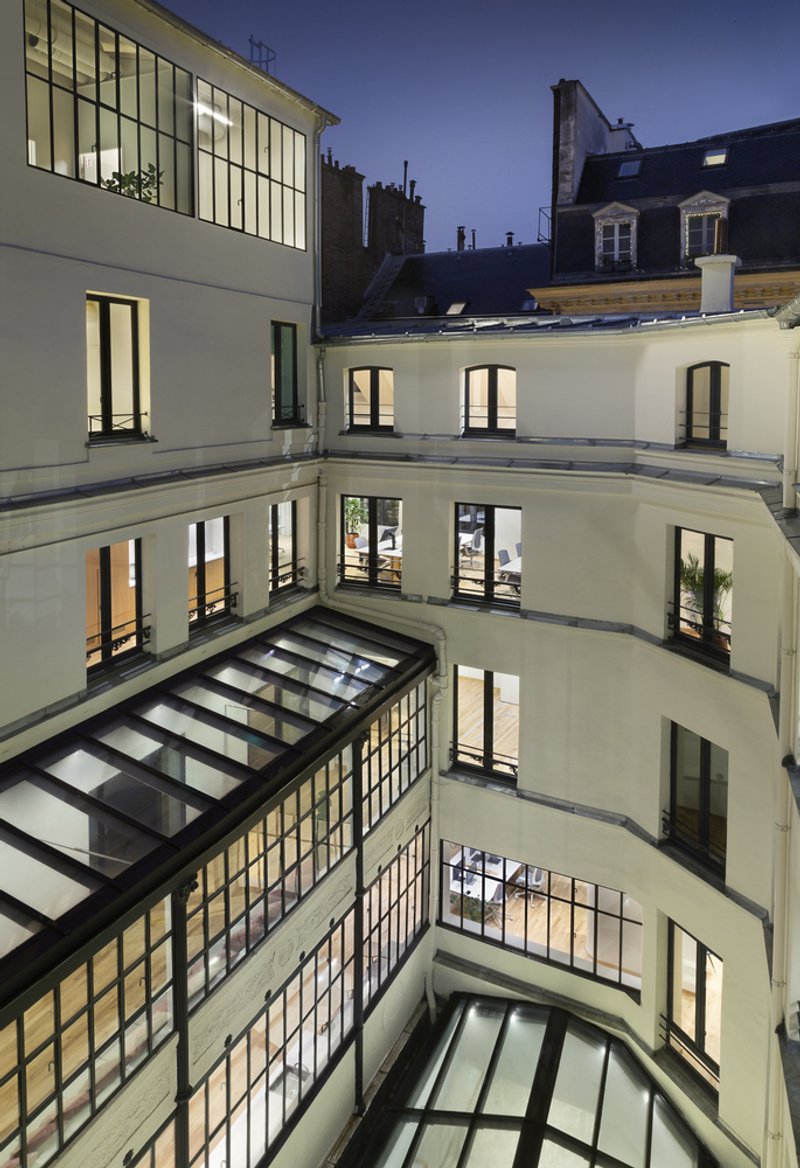 After: courtyard at night, lit windows on three sides, glass roof below