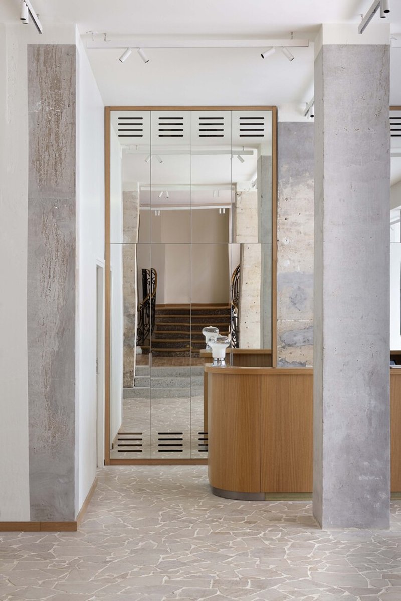 After: oak and concrete reception desk with ventilation grilles, staircase beyond