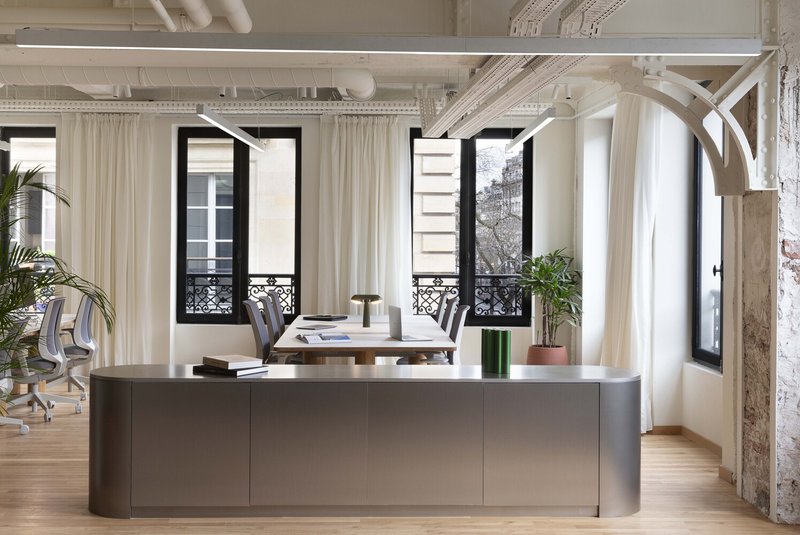 After: executive office with grey island desk, French doors to balcony, white curtains, exposed arched beam