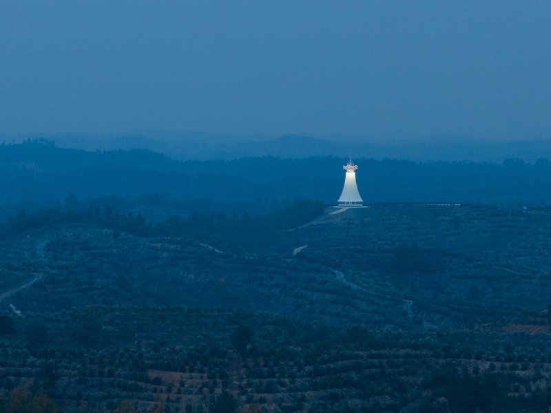 Tower at blue hour: the glowing white form seen from kilometres away, a beacon on the dark hilltop