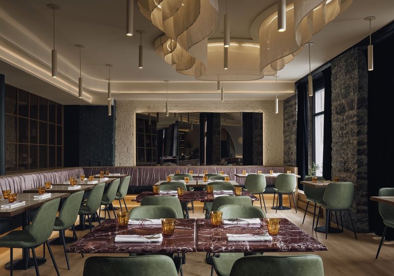 Dining room interior with spiraling layered pendant fixtures and set tables beneath a cove-lit ceiling