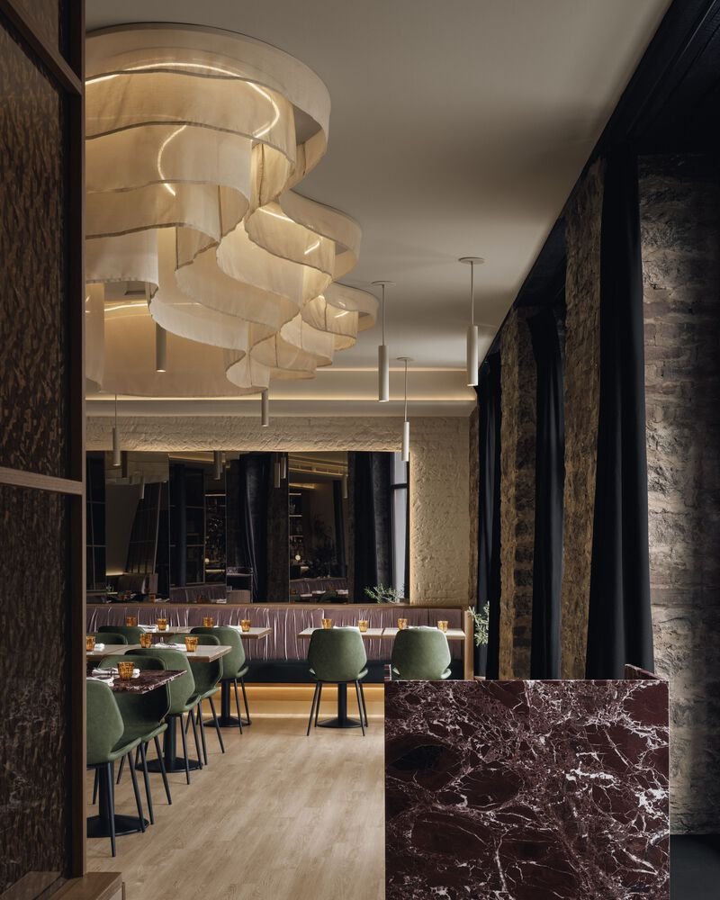 View toward the dining area showing layered sculptural lighting and a dark veined marble partition