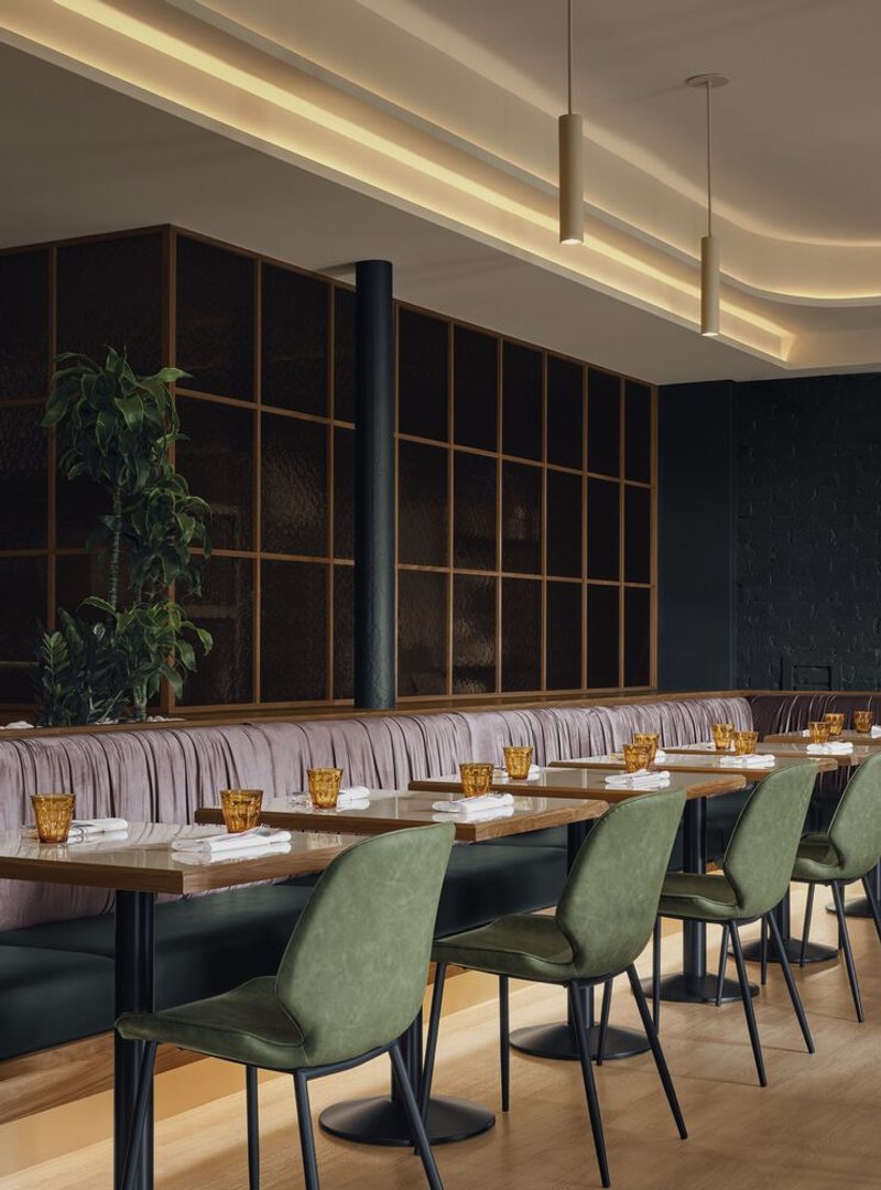 Dining area with timber grid partition, striped banquette seating, and pendant lights under curved ceiling
