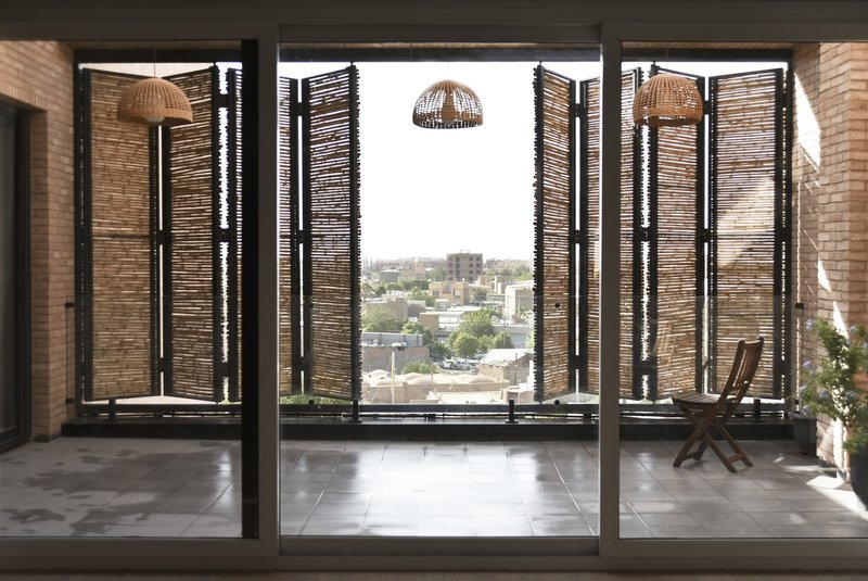 Interior view through sliding glass doors to balcony with folding reed screens and woven pendant lights